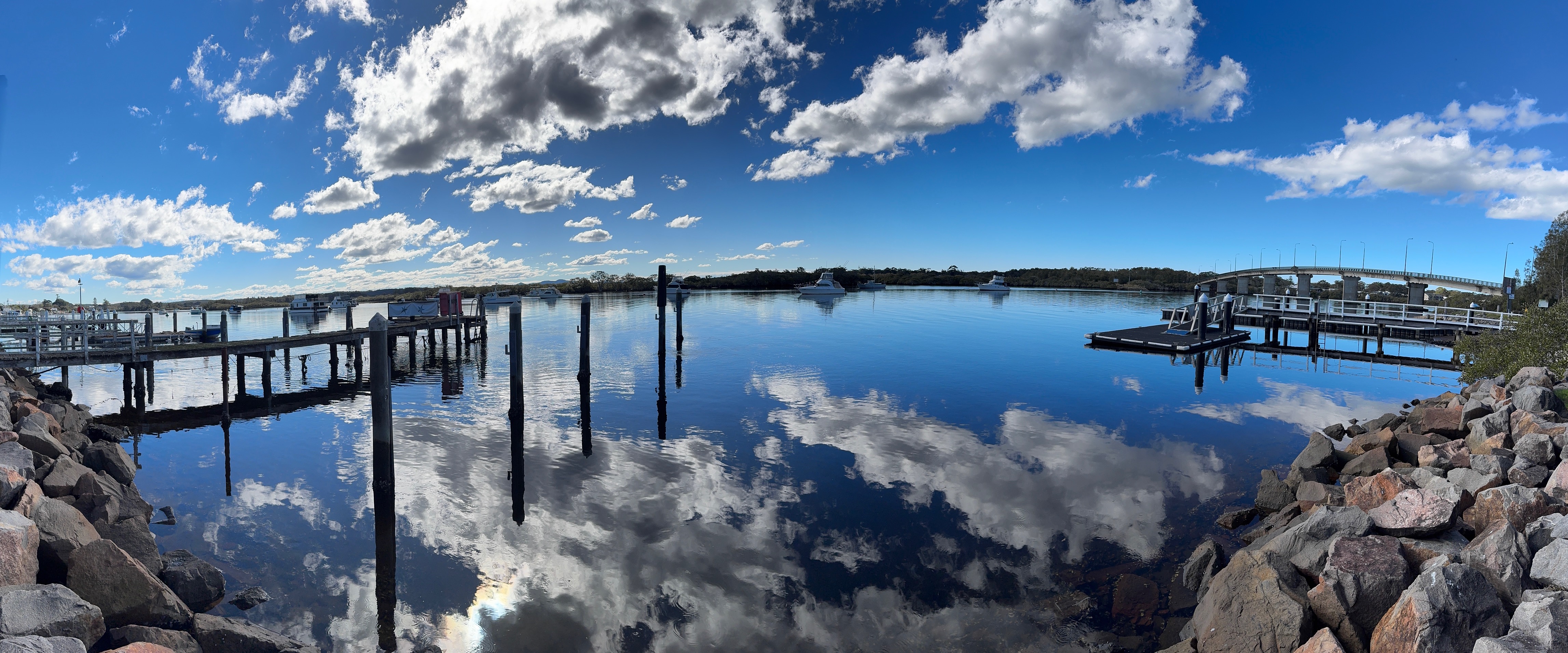 Marina jetty with cloud reflections on calm water at Tea Gardens